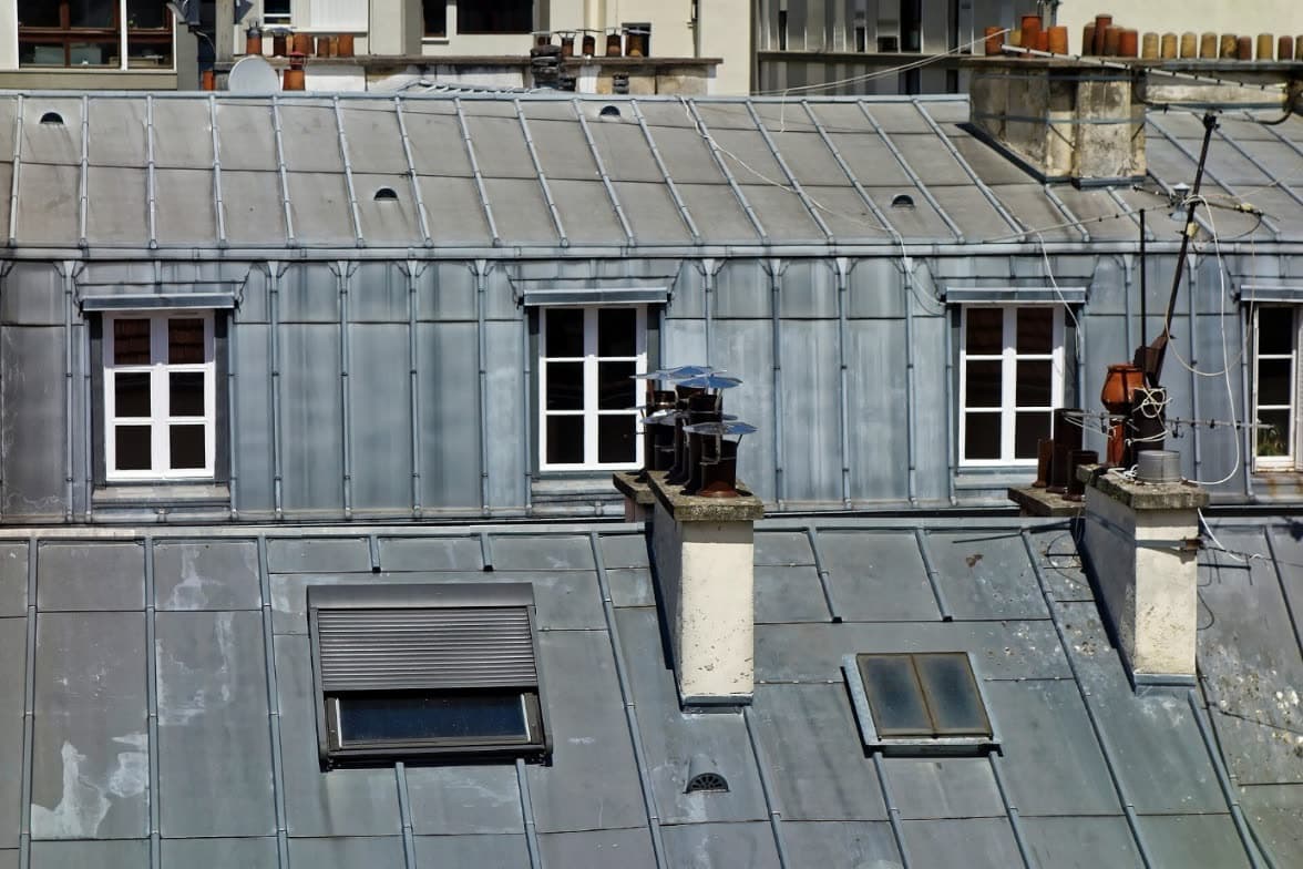 Toits en zinc d’immeubles parisiens avec souches de cheminée et fenêtres de toit